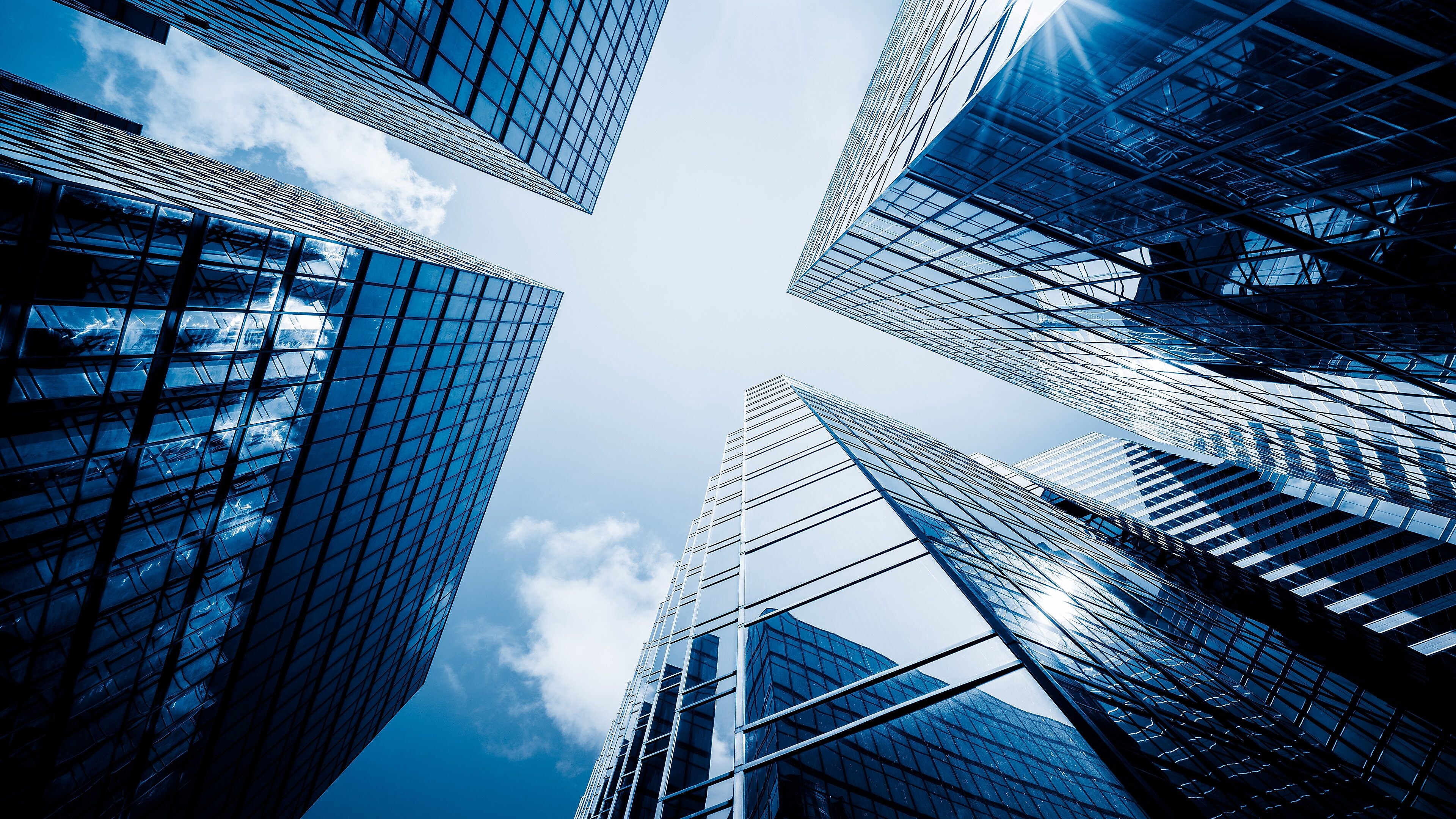 Looking up at the sky between reflective buildings