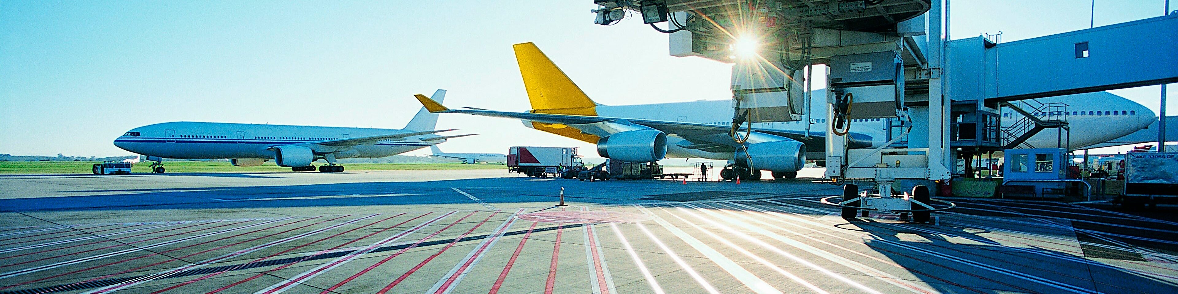 View of an airport runway in the early morning with the sun rising over two aeroplanes