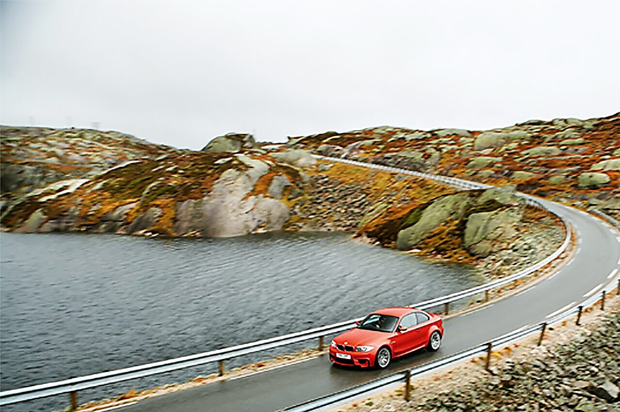 Red coloured car on a riverside road