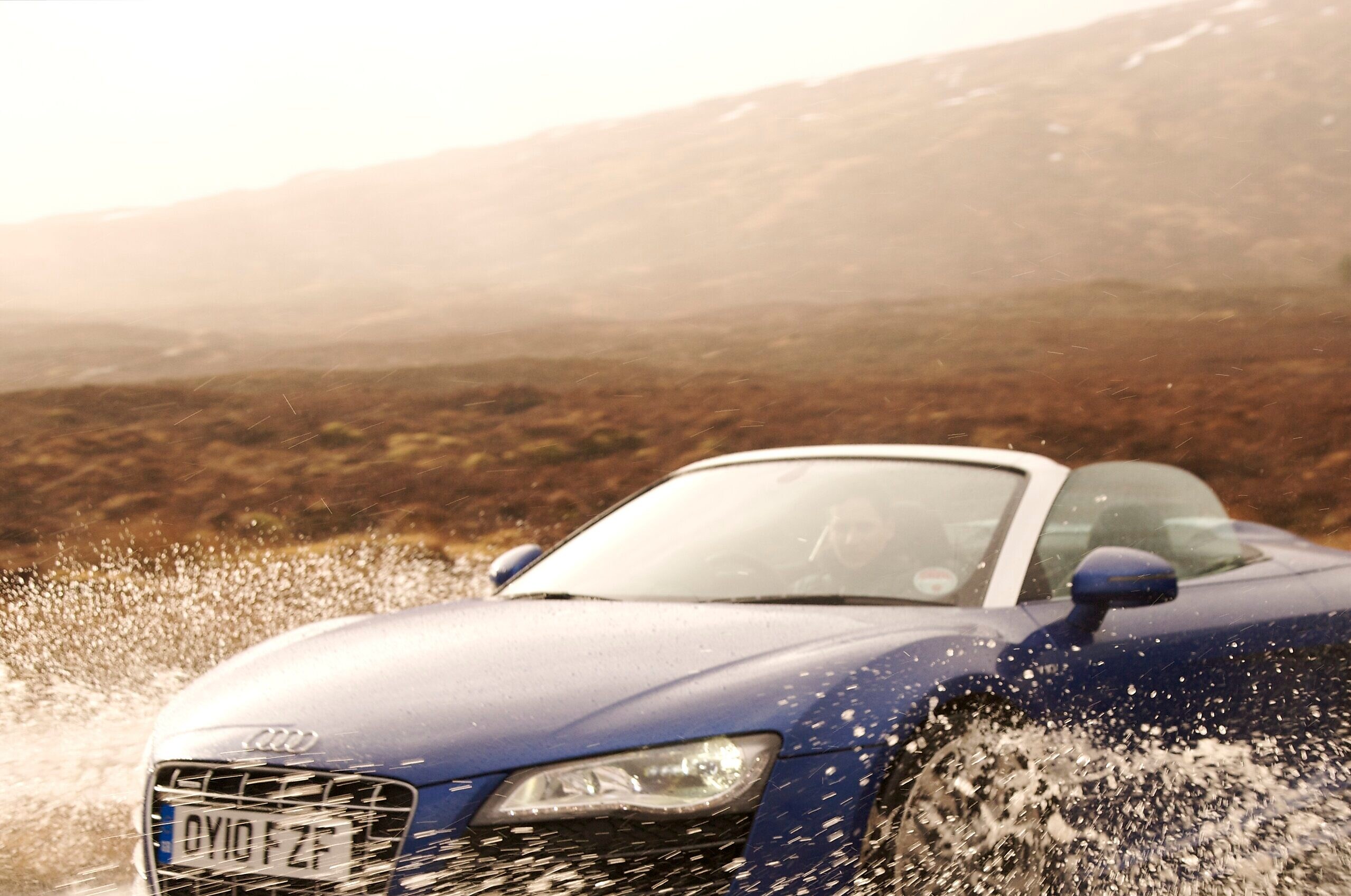 Man driving a car through a large puddle of water