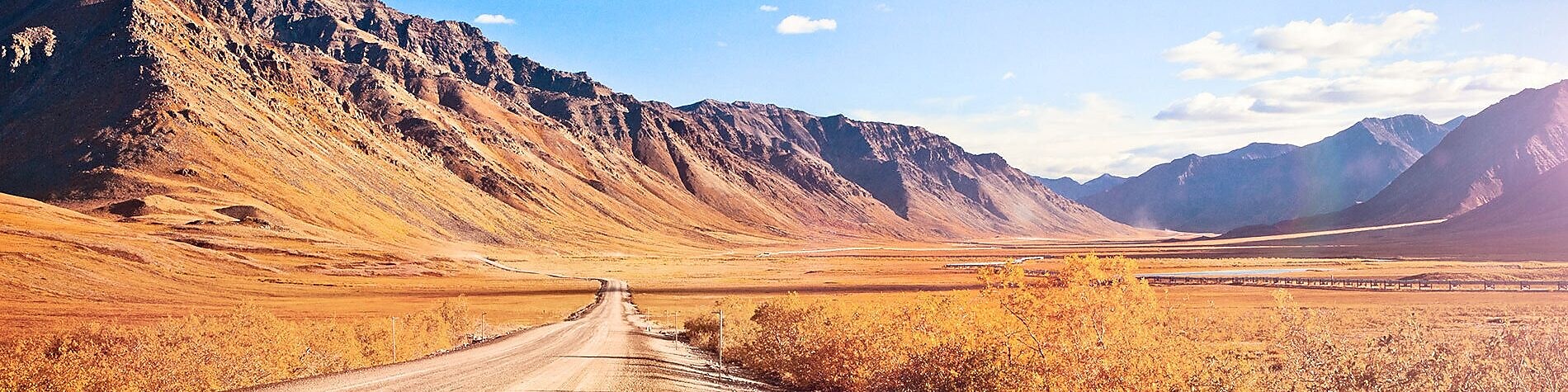 Empty dirt road surrounded by mountains