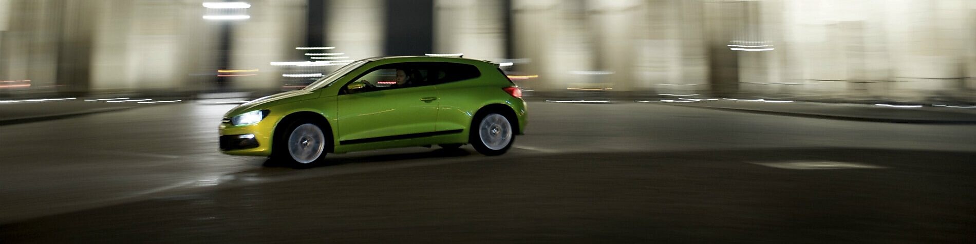 green car driving fast at night